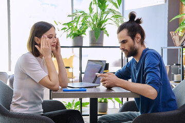 Serious sad upset young couple sitting together in cafeteria