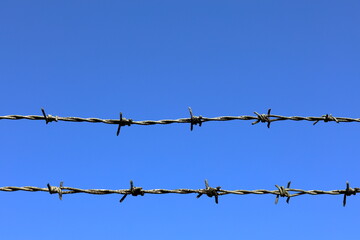 Barb wire fence. Blue sky as background.