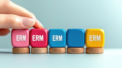 A hand adjusts colorful blocks with the letters "ERM" on a light background, representing a concept of organization or categorization.