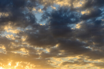 Majestic clouds illuminated by the warm glow of sunset across the evening sky in a tranquil expanse of nature