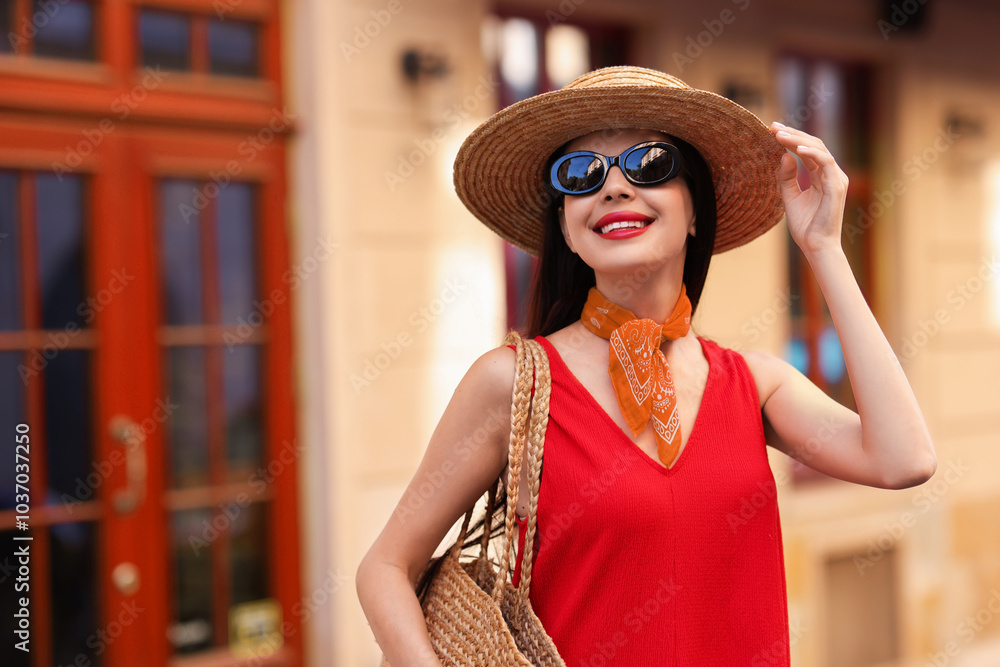 Sticker Smiling young woman in stylish hat and sunglasses on city street