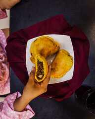 empanadas de harina rellenas de carne, en plato blanco cuadrado, sobre una tela color guinda.
