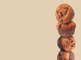 Stacked tasty chocolate chip muffins on beige background. Space for text
