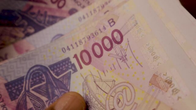 Closeup shot of black African hands counting 10000 West African cfa franc notes