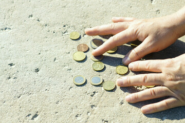A man counts coins poured out of a piggy bank onto the surface. Small savings: men's hands sort through coins of 1 (one) euro, 50, 20, 10 and 5 cents, close-up photo.