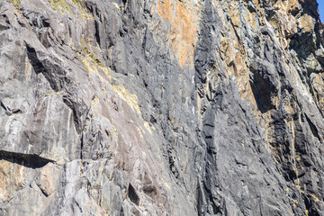 Sunlight illuminating a large rock face covered in vegetation