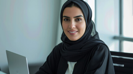 Portrait of a smiling beautiful young Arab woman wearing hijab in an office background	