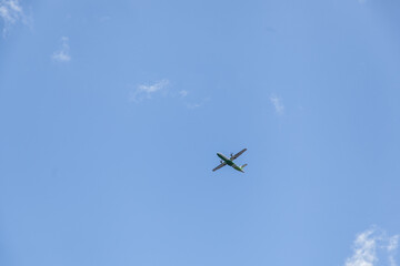 Green and white airplane flying in the blue sky