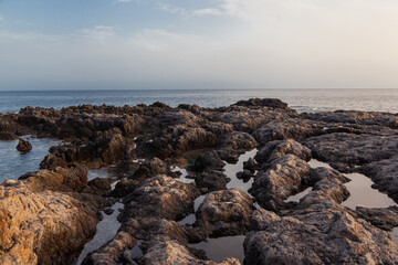 Ocean water filling puddles in volcanic rocks on cloudy day