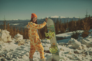 Naklejka premium A girl with a snowboard in her hands against the backdrop of snowy mountains