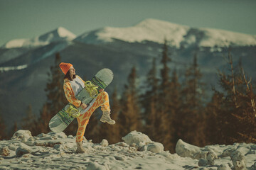  A girl with a snowboard in her hands against the backdrop of snowy mountains
