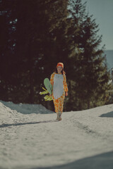  A girl with a snowboard in her hands against the backdrop of snowy mountains