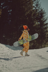  A girl with a snowboard in her hands against the backdrop of snowy mountains
