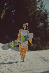  A girl with a snowboard in her hands against the backdrop of snowy mountains