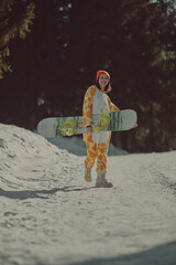 A girl with a snowboard in her hands against the backdrop of snowy mountains