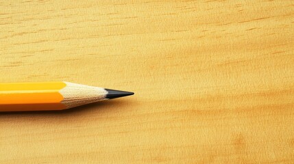 Obraz premium Yellow pencil on wooden background with sharp tip