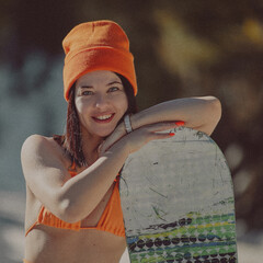  A girl with a snowboard in her hands against the backdrop of snowy mountains