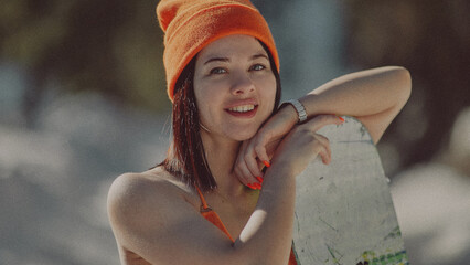  A girl with a snowboard in her hands against the backdrop of snowy mountains
