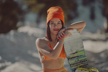  A girl with a snowboard in her hands against the backdrop of snowy mountains
