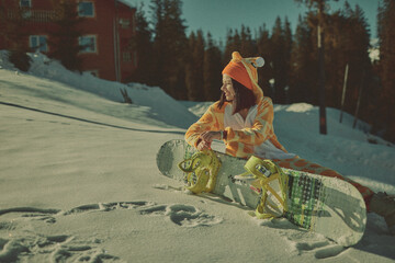  A girl with a snowboard in her hands against the backdrop of snowy mountains