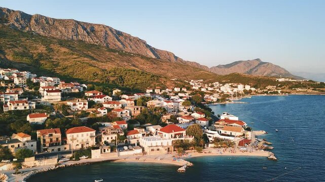 Aerial view of the small Croatian village Dugi Rat and its beach at sunset in summertime