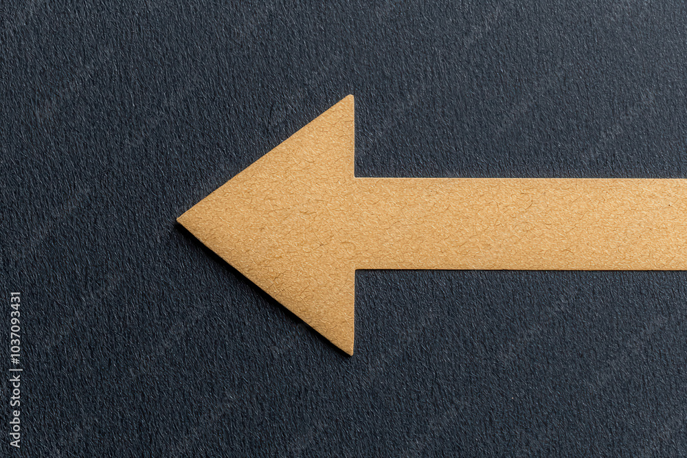 Poster A golden arrow shape pointing left on a textured dark surface, suggesting direction or navigation.