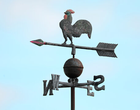 vintage metal weathervane featuring a rooster with a large tail on top along with an arrow and cardinal direction letters