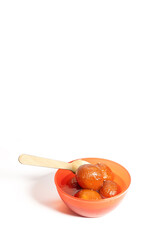 Traditional Indian dessert Gulab Jamun in red bowl with wooden spoon on white background