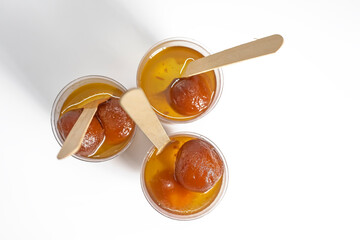 Gulab jamun in sugar syrup in three glasses with wooden spoons