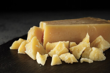Authentic Italian Parmigiano Reggiano: Aged Cheese Slice on Black and Wooden Backgrounds