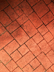 A close-up view of a textured red brick pattern on a paved surface, showcasing intricate designs and warm tones, perfect for design projects..