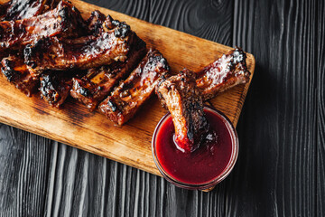 Rustic Grilled BBQ Ribs with Red Sauce Pork and Beef Roasted on Charcoal Wooden Background...
