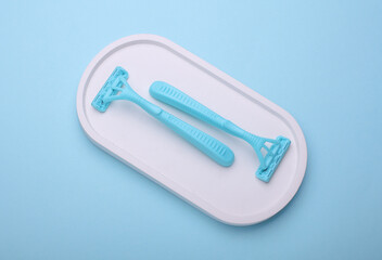 Blue disposable razors in plaster tray, blue background.