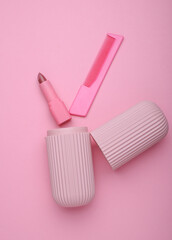 Organizer case with lipstick and comb on pink background
