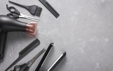 Flat lay hairdressing tools and accessories for hair styling on gray background. Top view. Copy...