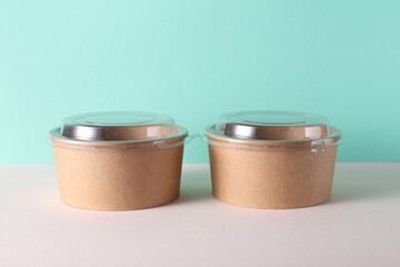 Cardboard round food boxes with plastic lid on table, turquoise background