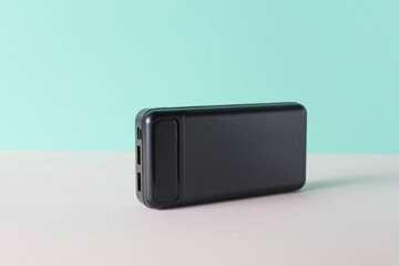 Black external battery power bank on mint green background