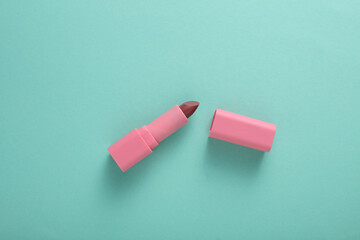 Tube of pink lipstick on mint green background
