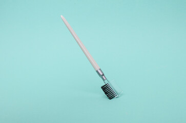 Makeup brush for eyebrows floating on mint green background