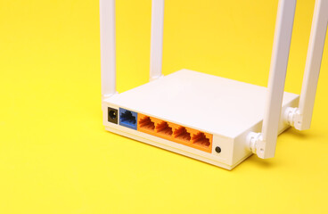 Modern four-antenna Wi-Fi router with sockets on yellow background
