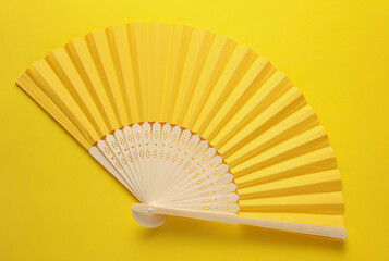 Traditional open yellow Asian hand fan on yellow background