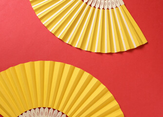 Traditional yellow Asian hand fans on red background