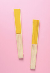 Traditional yellow Asian hand fans on pink background