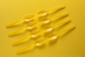 Set of plastic spoons on yellow background