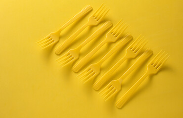 Set of plastic forks on yellow background