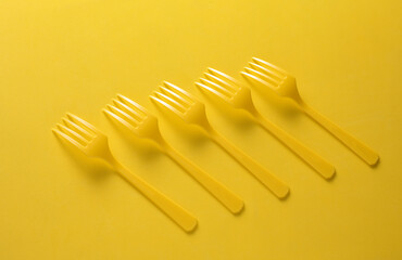 Set of plastic forks on yellow background