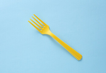 Yellow Plastic fork on blue background close up