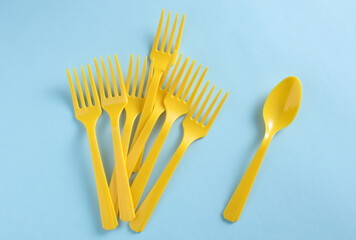 Many Yellow Plastic forks and spoon on blue background. Top view