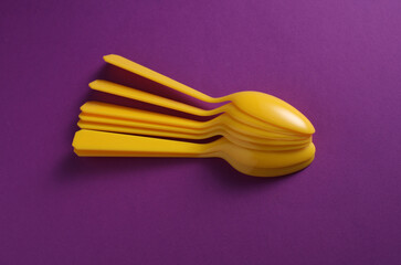 Yellow Plastic spoons on purple background.