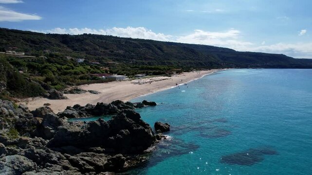 4K Aerial drone video of one of the most beautiful beaches in the world with turquoise clear blue water and white sand with big rocks on a sunny summer day. Marinella di Zambrone Paradiso Tropea Italy